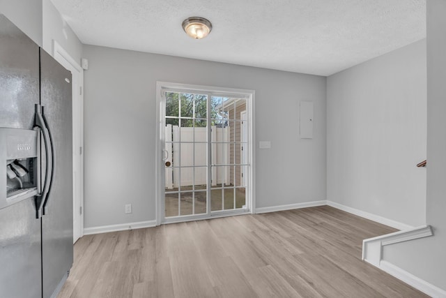 unfurnished dining area with light hardwood / wood-style floors and a textured ceiling