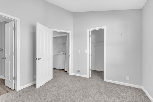 unfurnished bedroom featuring washing machine and clothes dryer, a spacious closet, lofted ceiling, light carpet, and a closet