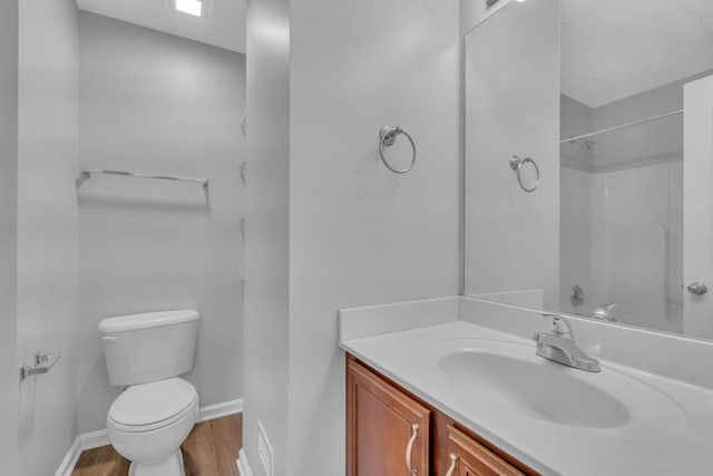 bathroom featuring a shower, hardwood / wood-style flooring, vanity, and toilet