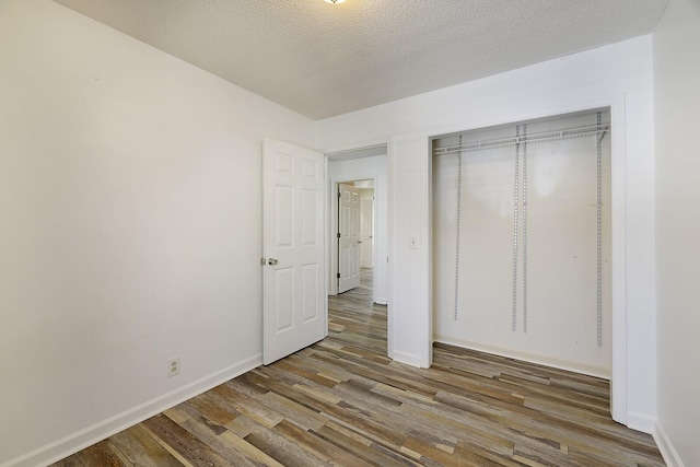 unfurnished bedroom with dark hardwood / wood-style flooring and a textured ceiling