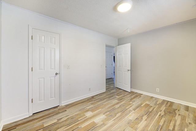 empty room with light hardwood / wood-style flooring and a textured ceiling