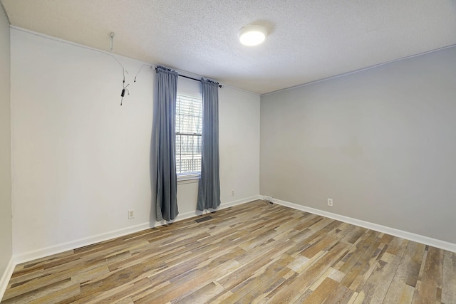 empty room featuring a textured ceiling and light hardwood / wood-style flooring