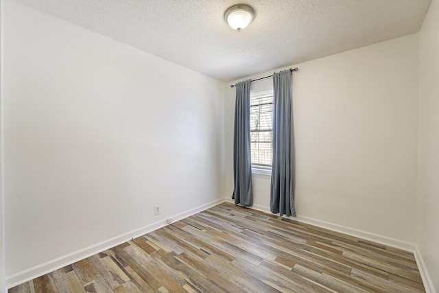 spare room featuring hardwood / wood-style floors and a textured ceiling