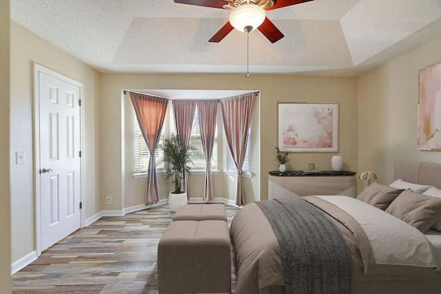 bedroom featuring a raised ceiling, ceiling fan, and light hardwood / wood-style floors