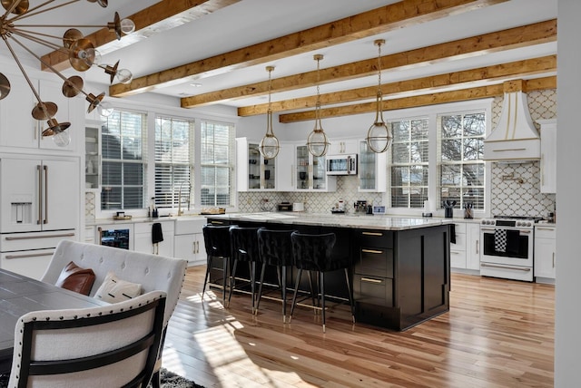 kitchen with a center island, white appliances, white cabinets, hanging light fixtures, and a kitchen bar