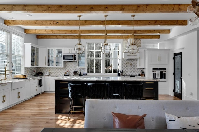 kitchen featuring a center island, sink, hanging light fixtures, beamed ceiling, and oven