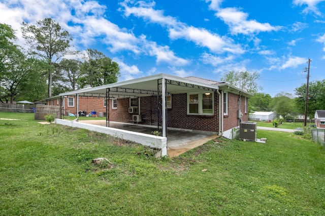 back of house with a carport, central AC unit, and a lawn