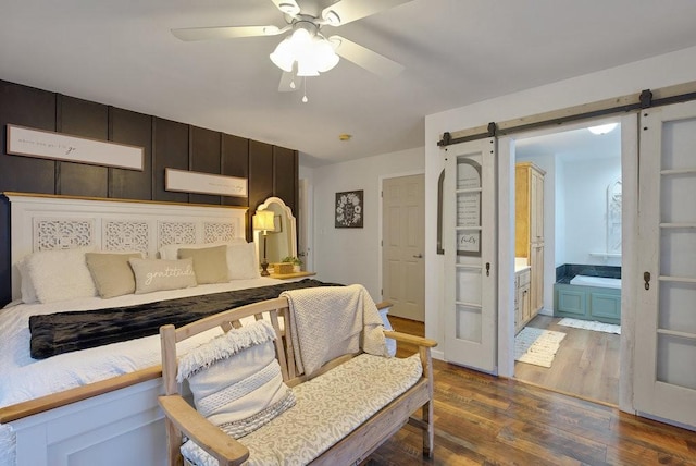 bedroom with ceiling fan, connected bathroom, hardwood / wood-style flooring, and a barn door