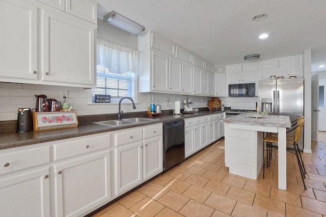 kitchen featuring white cabinets, black appliances, sink, a kitchen breakfast bar, and light tile patterned floors