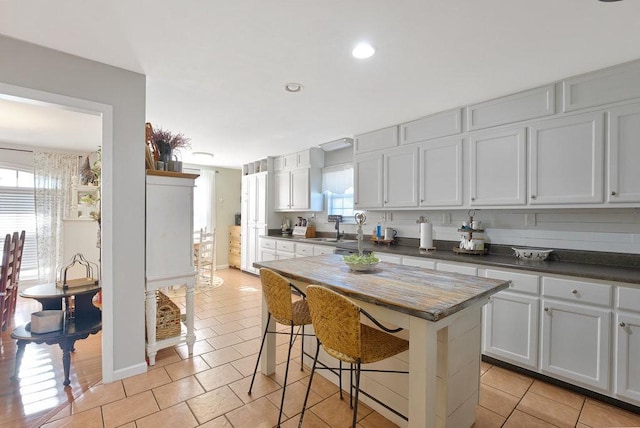 kitchen with a center island, white cabinetry, a healthy amount of sunlight, sink, and a breakfast bar area