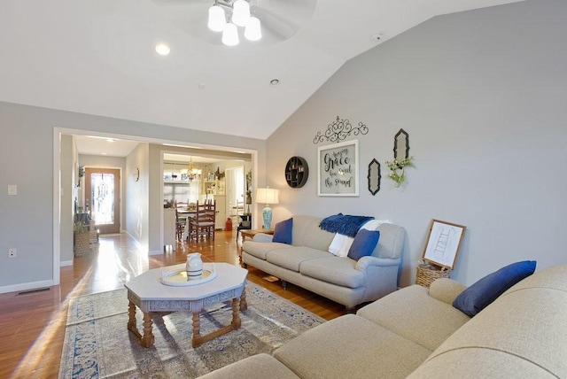 living room with vaulted ceiling, ceiling fan with notable chandelier, and wood-type flooring