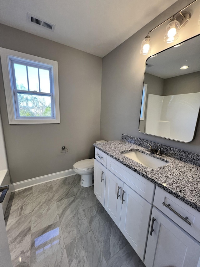 bathroom with vanity, toilet, and a shower