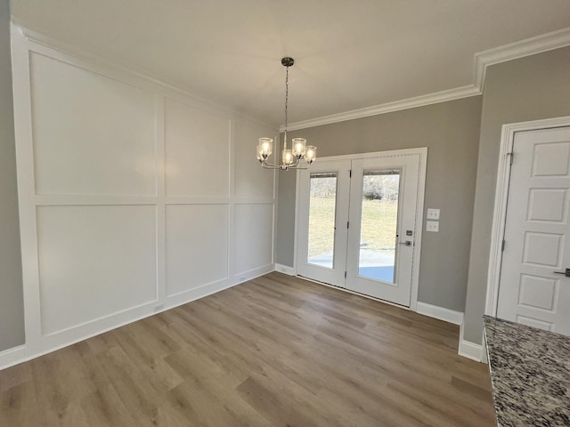 unfurnished dining area featuring a notable chandelier, ornamental molding, and light hardwood / wood-style flooring