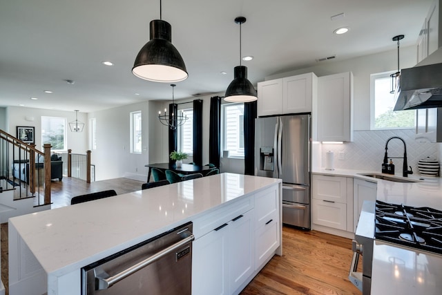 kitchen featuring stainless steel appliances, sink, an inviting chandelier, white cabinets, and a kitchen island