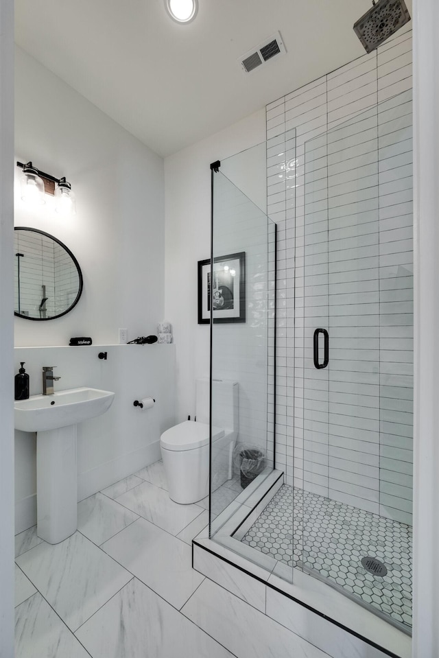 bathroom with toilet, a shower with shower door, and sink