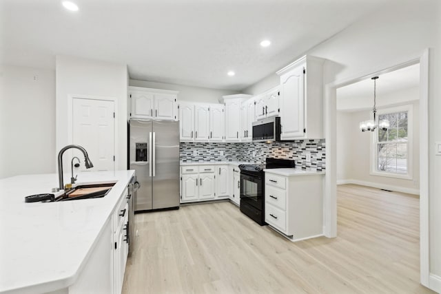 kitchen featuring appliances with stainless steel finishes, decorative light fixtures, white cabinetry, and sink