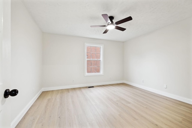 empty room with ceiling fan, light wood-type flooring, and a textured ceiling