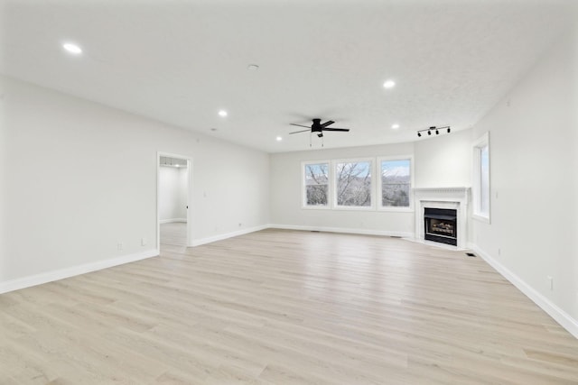 unfurnished living room with light wood-type flooring, rail lighting, and ceiling fan