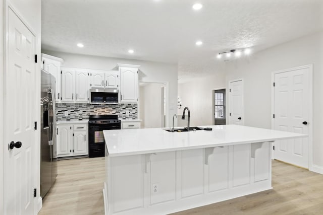 kitchen with backsplash, a kitchen island with sink, white cabinets, appliances with stainless steel finishes, and a kitchen bar