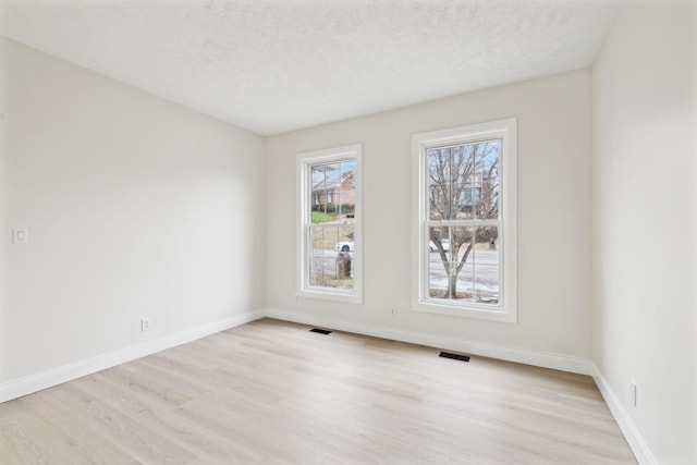 spare room with light hardwood / wood-style floors and a textured ceiling