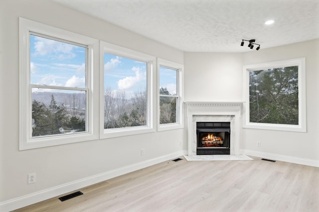 unfurnished living room featuring light hardwood / wood-style flooring and a textured ceiling