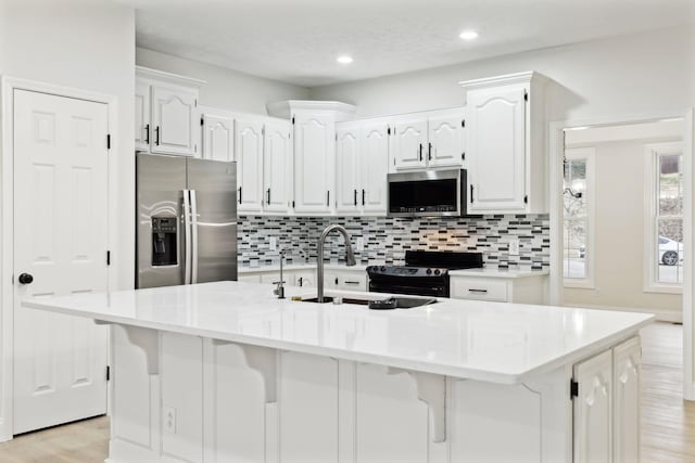 kitchen featuring a center island with sink, sink, white cabinetry, and stainless steel appliances