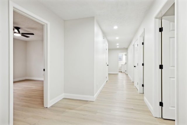 hallway featuring a textured ceiling and light hardwood / wood-style flooring