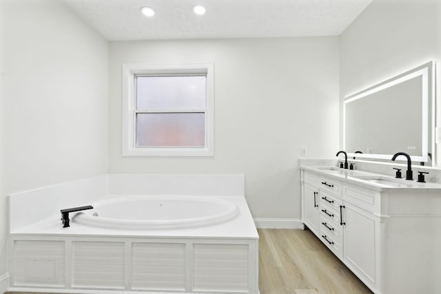 bathroom with a textured ceiling, vanity, a tub to relax in, and hardwood / wood-style flooring