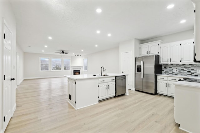 kitchen featuring ceiling fan, sink, stainless steel appliances, backsplash, and white cabinets