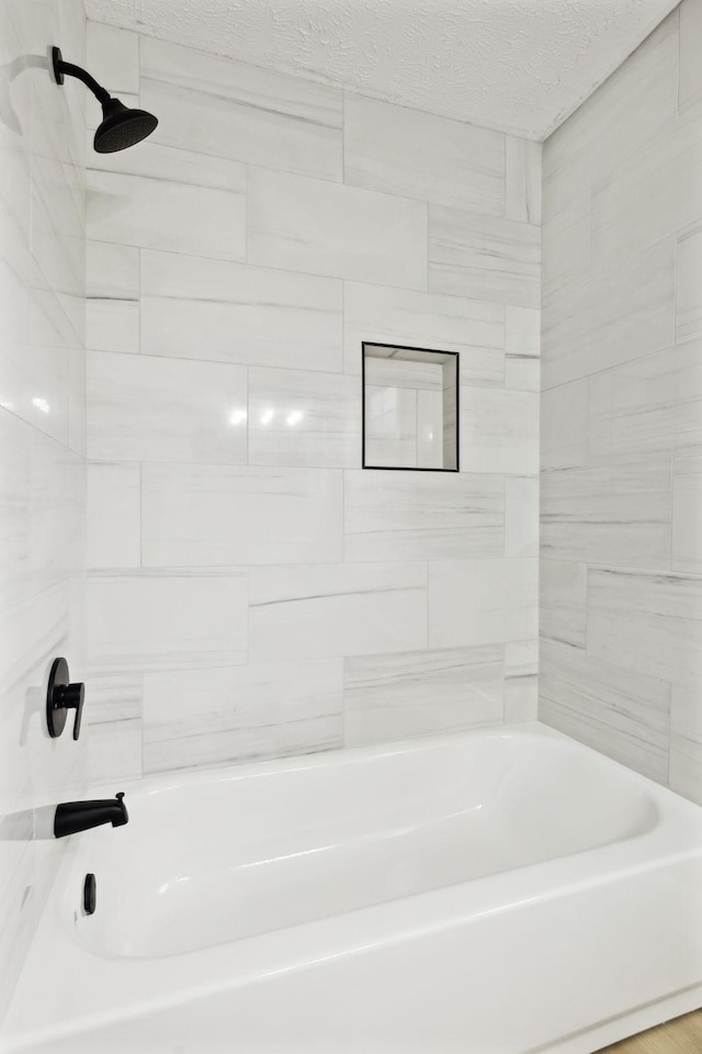 bathroom with a textured ceiling and bathtub / shower combination