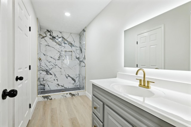 bathroom featuring tiled shower, vanity, and hardwood / wood-style flooring