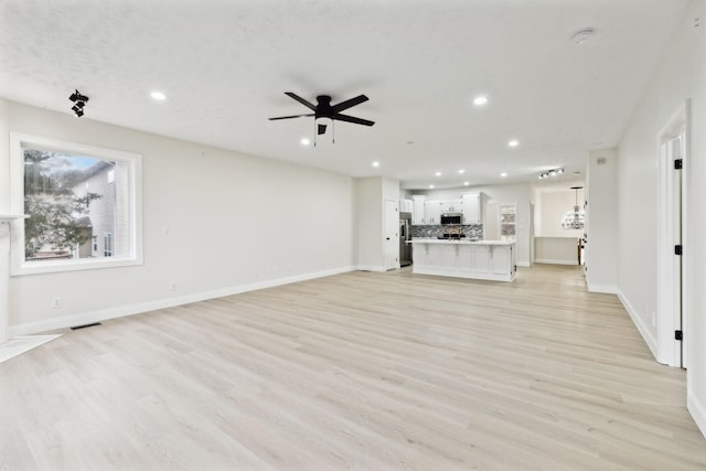 unfurnished living room featuring light hardwood / wood-style flooring and ceiling fan