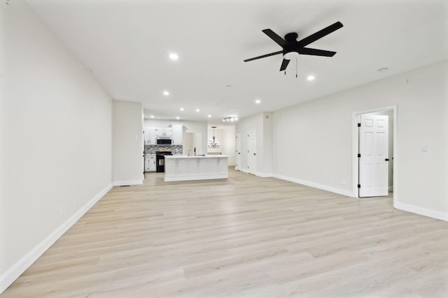 unfurnished living room with ceiling fan, sink, and light hardwood / wood-style flooring