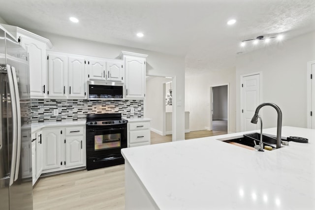 kitchen featuring sink, stainless steel appliances, decorative backsplash, white cabinets, and light wood-type flooring