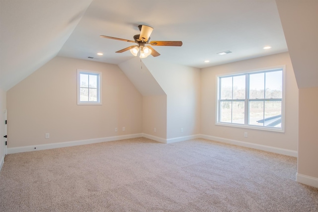 additional living space with ceiling fan, a healthy amount of sunlight, and light colored carpet