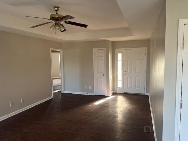 foyer featuring a tray ceiling, ceiling fan, and dark wood-type flooring