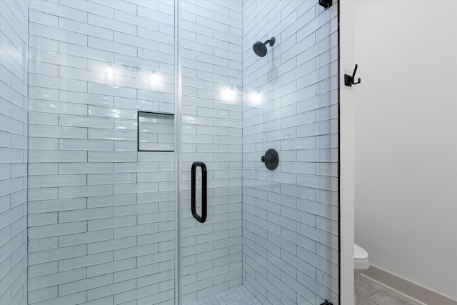 bathroom with tile patterned floors, toilet, and a shower with shower door