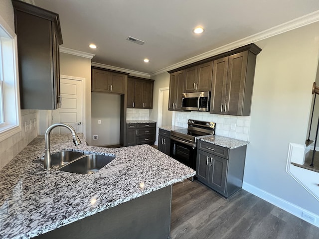 kitchen with appliances with stainless steel finishes, tasteful backsplash, light stone counters, and sink