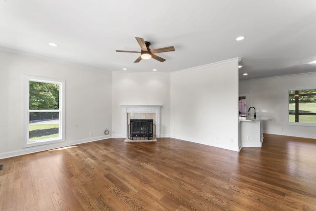 unfurnished living room with dark hardwood / wood-style floors, crown molding, and a tiled fireplace