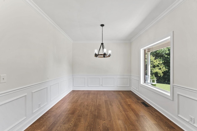 unfurnished dining area with dark hardwood / wood-style floors, crown molding, and a notable chandelier