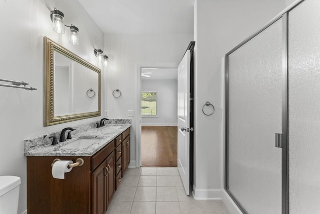 bathroom featuring tile patterned floors, vanity, toilet, and a shower with shower door