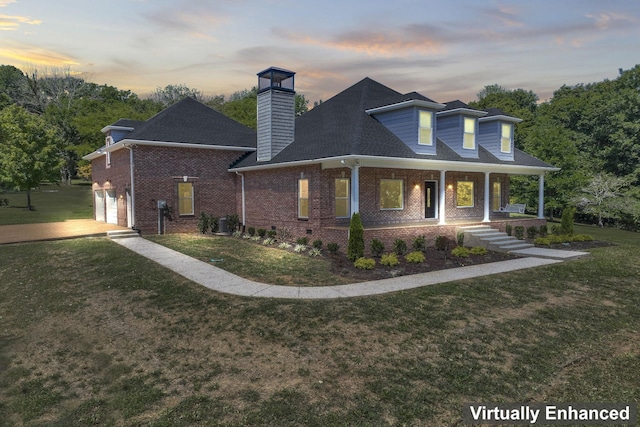 view of front of property featuring covered porch, a garage, and a yard