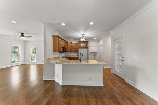 kitchen with light stone countertops, sink, ceiling fan, kitchen peninsula, and ornamental molding