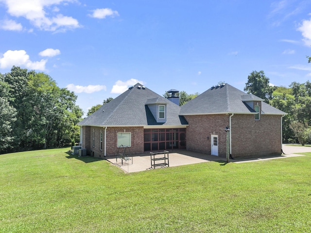 rear view of property with a lawn, a patio area, a sunroom, and central air condition unit