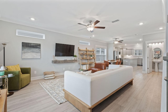 living room with ceiling fan, light wood-type flooring, and ornamental molding