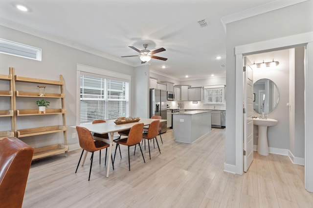 dining area with ceiling fan, light wood-type flooring, plenty of natural light, and crown molding