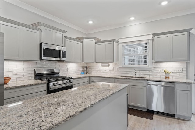 kitchen featuring gray cabinetry, sink, appliances with stainless steel finishes, tasteful backsplash, and light stone counters