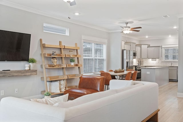 living room featuring light hardwood / wood-style floors, ceiling fan, and ornamental molding