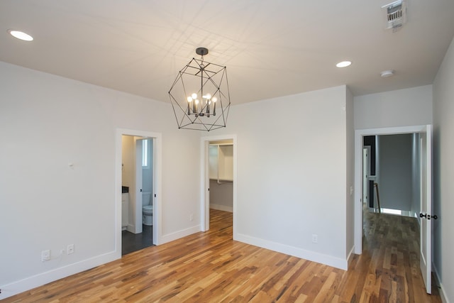 spare room with hardwood / wood-style floors and a chandelier