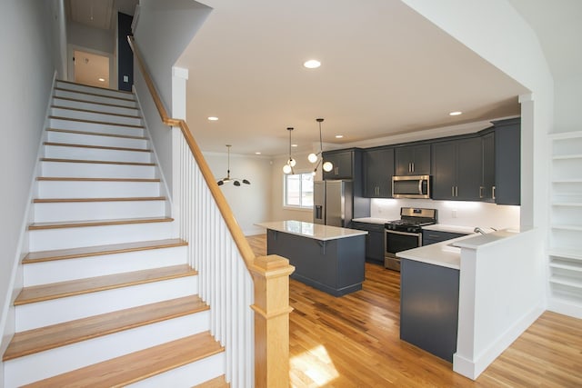 kitchen with light hardwood / wood-style floors, decorative light fixtures, a breakfast bar area, a kitchen island, and appliances with stainless steel finishes